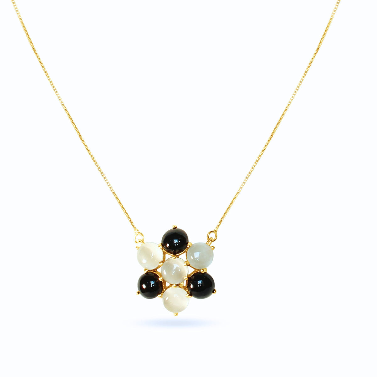 This ivory flower necklace pairs black and ivory cabochon petals on a warm gold chain — a floral necklace with real contrast and shine.