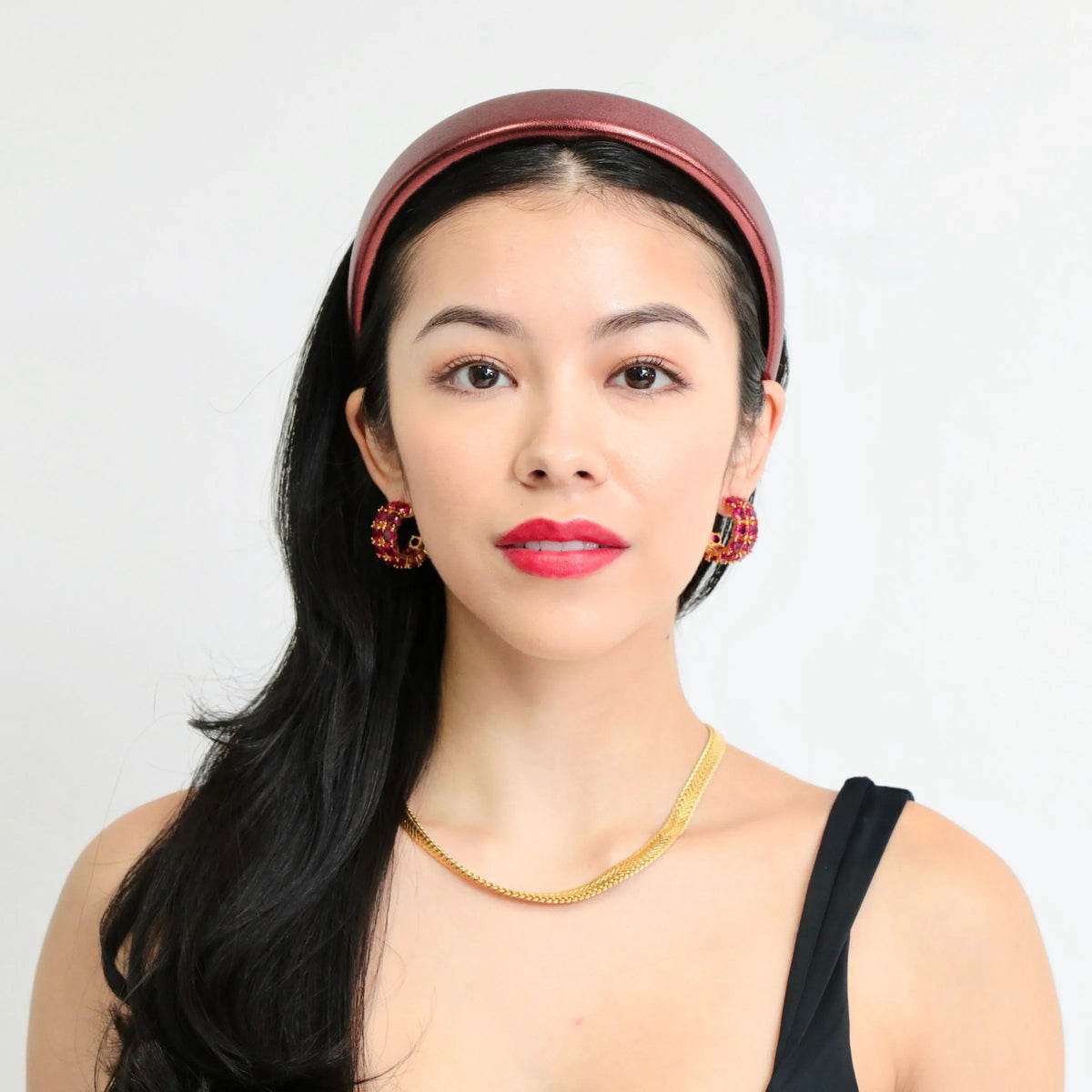 Red hoop earrings with diamond-cut cubic zirconia stones. Model is also wearing our red headband and gold snake chain to complete the look.