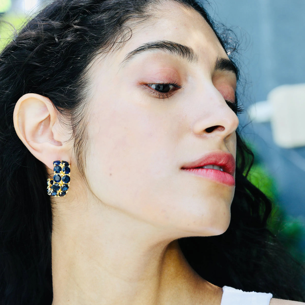 Close-up of gold sapphire earrings showing the faceted blue stones